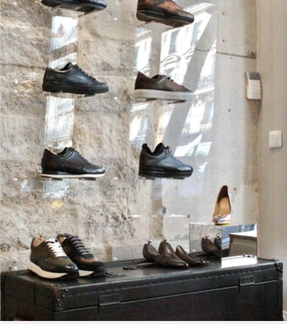 Souliers présentés sur des tablettes en verre devant un mur de pierre apparente